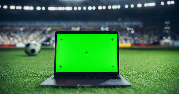 istock Laptop Computer with a Green Screen Mock Up Display with a Soccer Ball Rolling in the Background on a Stadium Field at Night. Template for Software, Streaming, Sports Betting, Multimedia Content 2205704981