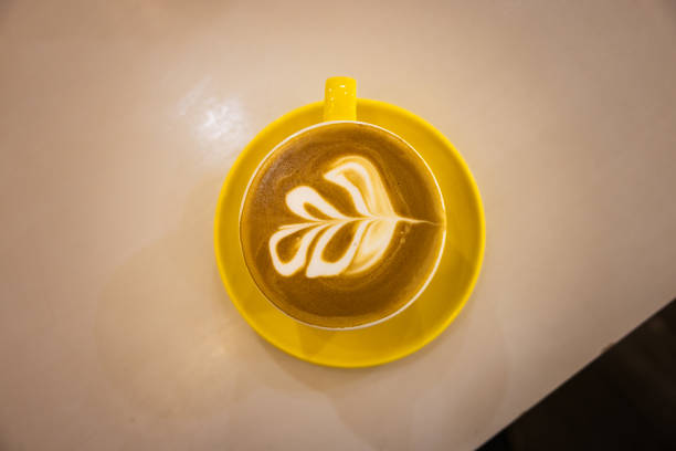Hot latte with coffee art stands on coffee shop table.