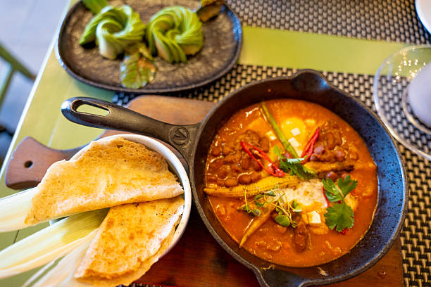 Spicy Curry Dish with Naan and Artistic Avocado Garnish in Restaurant Setting