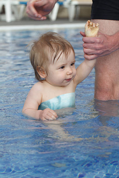 Father holding baby in swimming pool