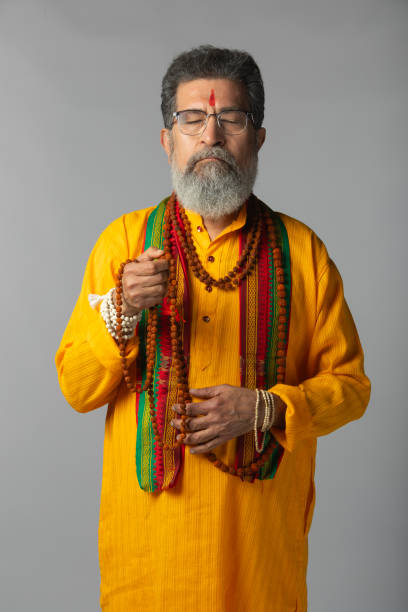 istock Old priest with eyes closed praying against white background 2205715611