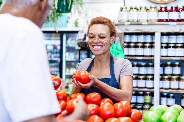 istock Friendly Latina Shopkeeper Assisting Customer with Tomatoes 2205717829