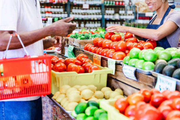 Customer and vendor interacting at a farmers market, selecting ripe tomatoes.