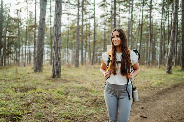 istock Young woman hike or trek and explore scenic forest with hiking sticks 2205719093
