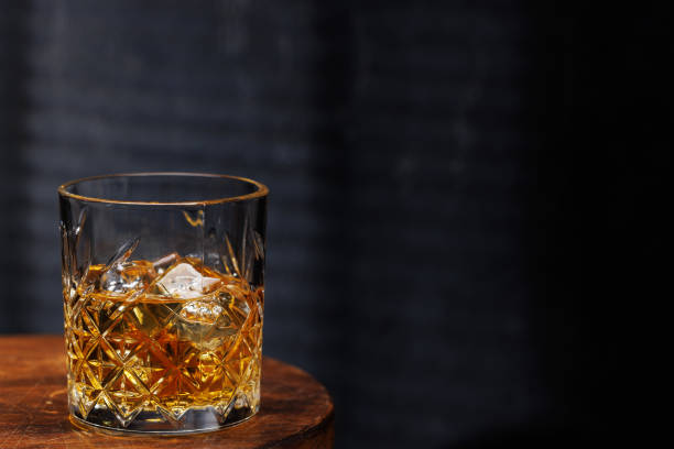 istock A whiskey glass resting on a wooden table, set against a dark background 2205719425