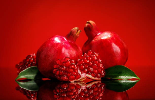 istock A ripe, glossy pomegranate placed against a vibrant red background 2205720178