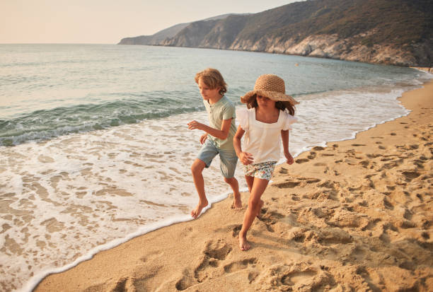 istock Children run down a tropical paradise beach during sunset 2205728694