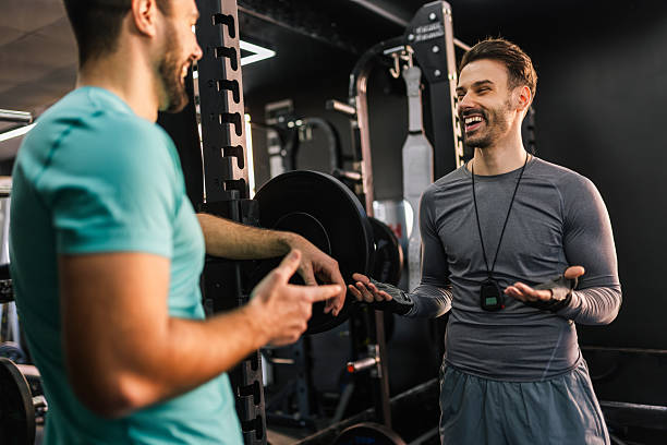 istock Athletic man talks with the personal trainer in the gym. 2205730590