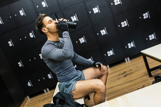 istock Man drinks pre workout drink in the dressing room. 2205730751