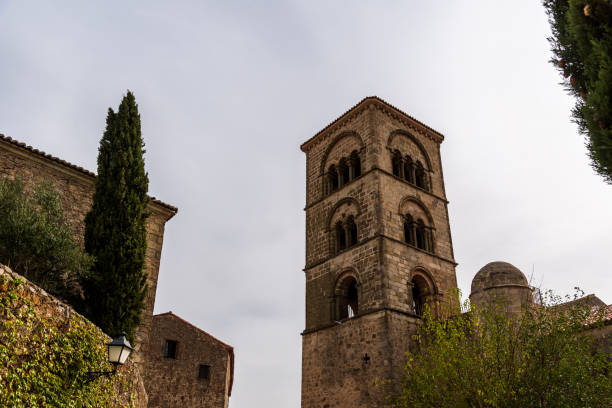 An upward view captures the architecture of Trujillo, Extremadura, showcasing a bell tower and stone buildings against a bright sky.