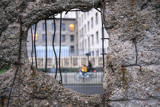 istock Hole in Broken Berlin wall and walking person against 2205733646