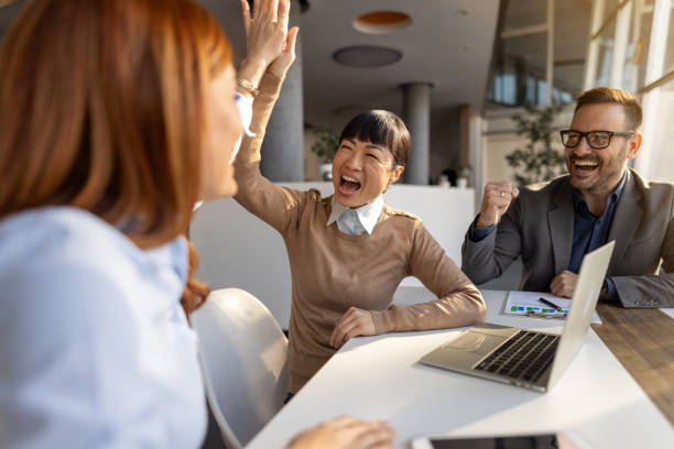 istock Excited business team celebrating success with high five in office 2205734606