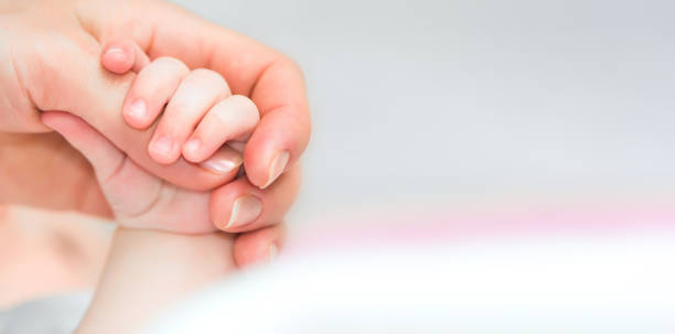 istock baby holds mother's finger 2205736176