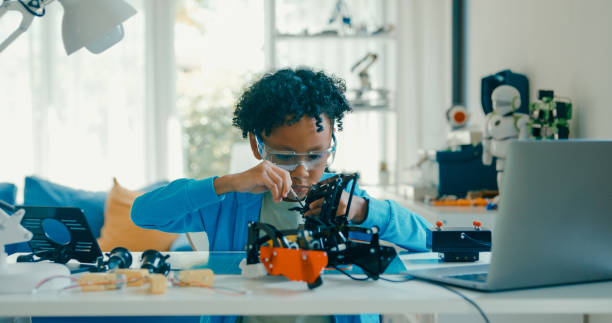 istock Young African-American boy in STEM education by assembling robot at home. STEM Education robotics courses online. 2205736361