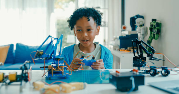 istock Young African-American boy explains robotics project, showcasing creation while discussing technology and innovation from home. STEM Education robotics courses online. 2205736401