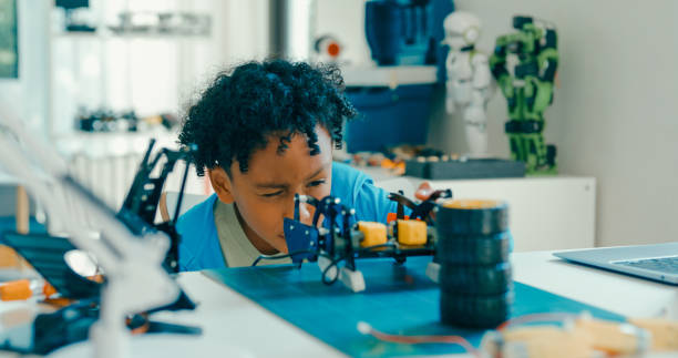 istock Young African-American boy in STEM education by assembling robot at home. STEM Education robotics courses online. 2205736404