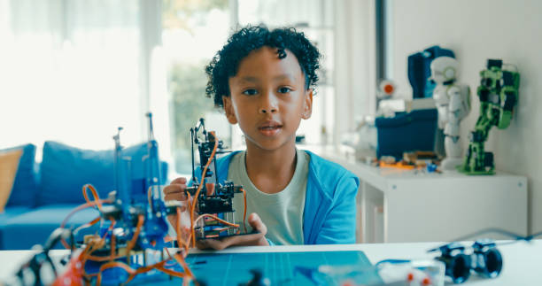 istock Young African-American boy explains robotics project, showcasing creation while discussing technology and innovation from home. STEM Education robotics courses online. 2205736406