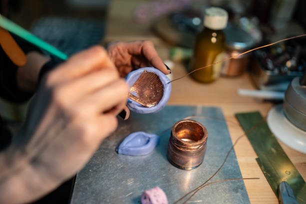 istock Artisan Applying Copper Paint to a Wire Mold on a Workspace 2205737290