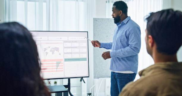 istock Group of business professionals meeting reviewing global data analytics discussing data analytics during a presentation, discussing strategy and growth standing at the office. Finance meeting concept. 2205738402
