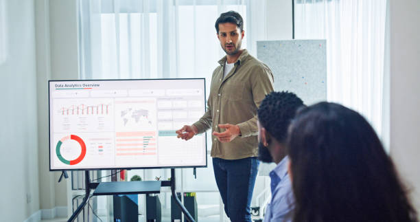 istock Group of business professionals meeting reviewing global data analytics discussing data analytics during a presentation, discussing strategy and growth standing at the office. Finance meeting concept. 2205738503
