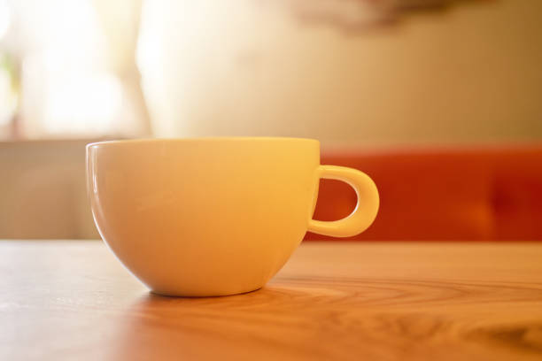 istock A ceramic cup rests on a smooth wooden table, illuminated by soft afternoon light. The warm ambiance suggests a perfect spot for enjoying beverages and relaxation 2205741726