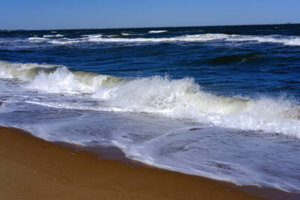 Seascape low front view of breaking wave and sandy beach on a sunny summer day.