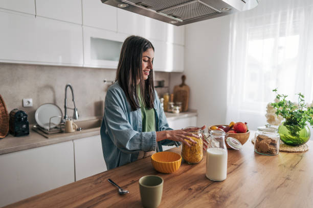 istock Young woman preparing breakfast with milk and cereals in kitchen 2205745963