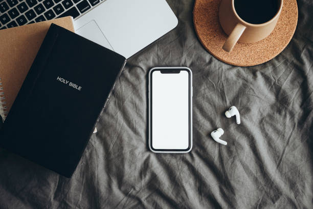 istock The Bible, phone with white blank screen on the bed, Holy book, online study. 2205746089