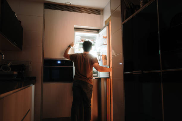 istock Man opening a fridge at night 2205747311