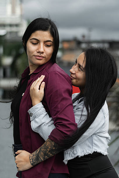 young latina lesbian couple, woman hugging her partner from behind while looking into each other's eyes