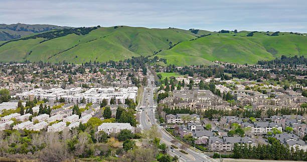istock Wide Road Cutting Between Apartment Complexes in Fremont, CA with Grassy Hills Beyond 2205747953