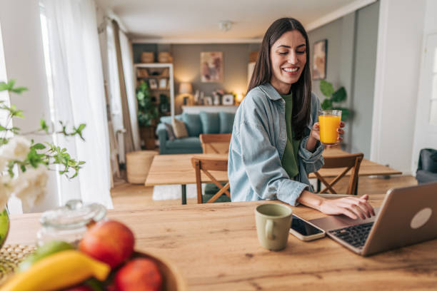 istock Young woman working remotely from home while drinking orange juice 2205748434