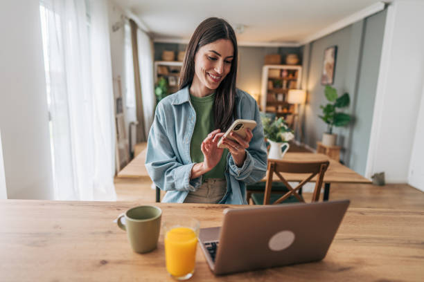 istock Young woman using smartphone and laptop at home 2205748509