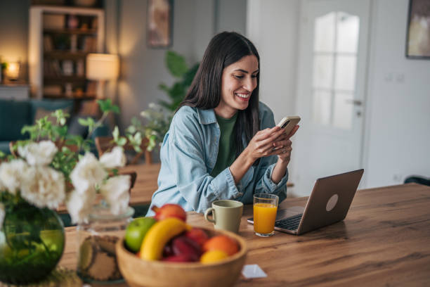 istock Young woman using smartphone and laptop at home 2205748668