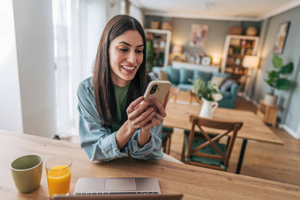 istock Young woman using smartphone and smiling while working from home 2205749488