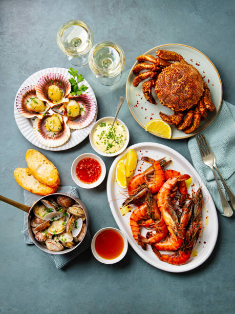 istock Seafood assortment. Prawns, crab, oysters, langoustines, scallops with white wine. Grey background. Top view. 2205751210