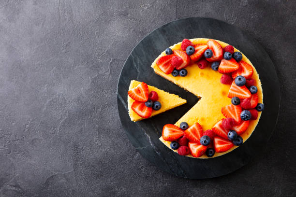 istock Cheesecake dessert with fresh berries on marble cutting board. Dark gray background. Copy space. Top view. 2205751420