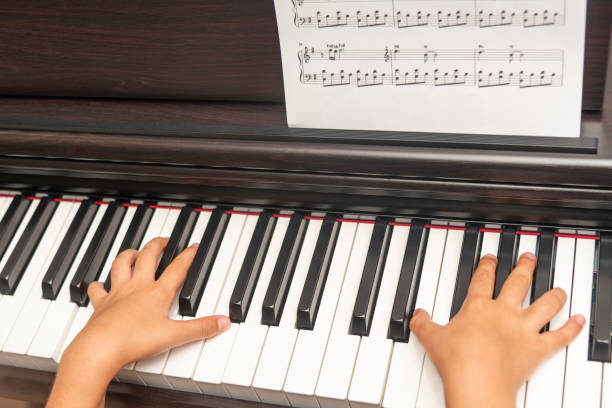 istock Cute boy playing piano at home and boy Playing Piano with Dramatic Lighting 2205753187
