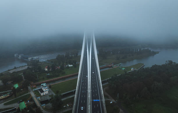 Aerial view of a cable-stayed bridge vanishing into thick fog over a river