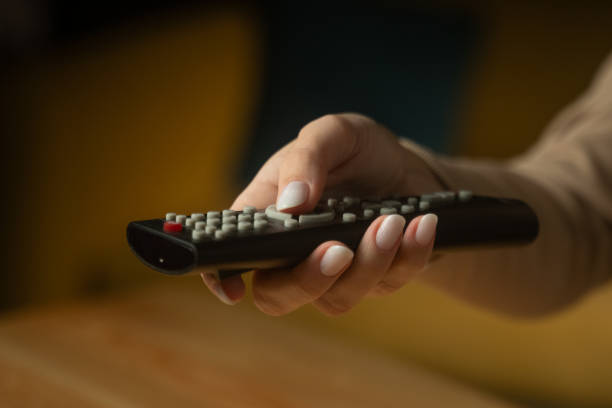 istock Hand reaching for remote control at home, ready to change channels or start a show 2205764133