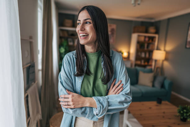 istock Young woman smiling and looking away while standing at home 2205765721