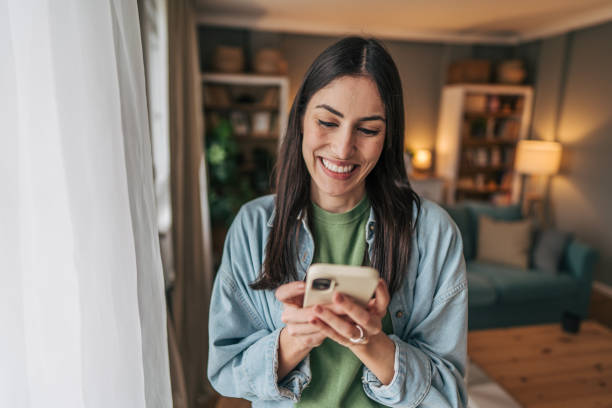istock Young woman using smartphone and smiling at home 2205765852