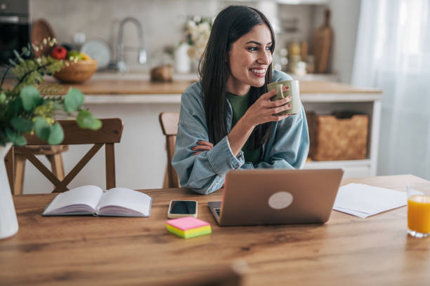 istock Young woman working remotely from home and drinking coffee 2205765975