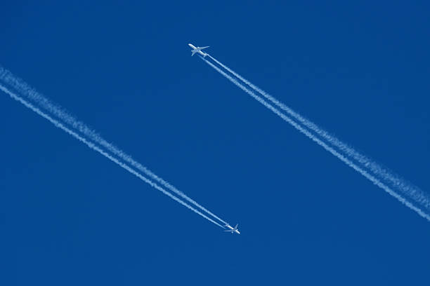 istock Airplanes in the blue sky with white contrail. Two contrails. Blue sky background. 2205766109