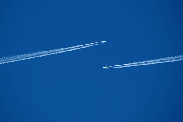 istock Airplanes in the blue sky with white contrail. Two contrails. Blue sky background. 2205766435