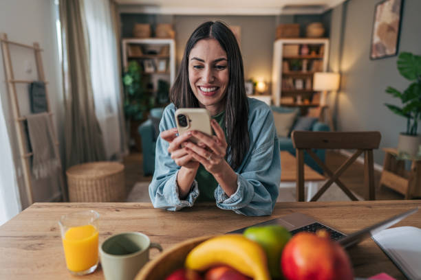 istock Young woman using smartphone and smiling at home 2205766447