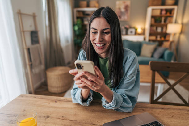 istock Young woman using mobile phone and smiling at home 2205766449