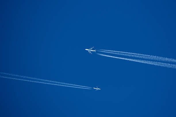 istock Airplanes in the blue sky with white contrail. Two contrails. Blue sky background. 2205766476