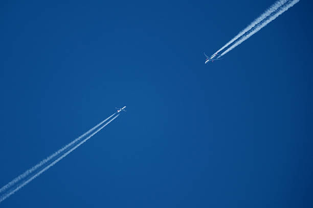 istock Airplanes in the blue sky with white contrail. Two contrails. Blue sky background. 2205766495