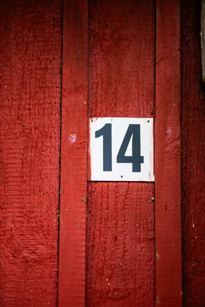 istock White plaque marked 14 on a red wooden house.. 2205766649